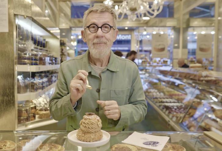Dans une pâtisserie, Jamy s'apprête à manger un paris-brest